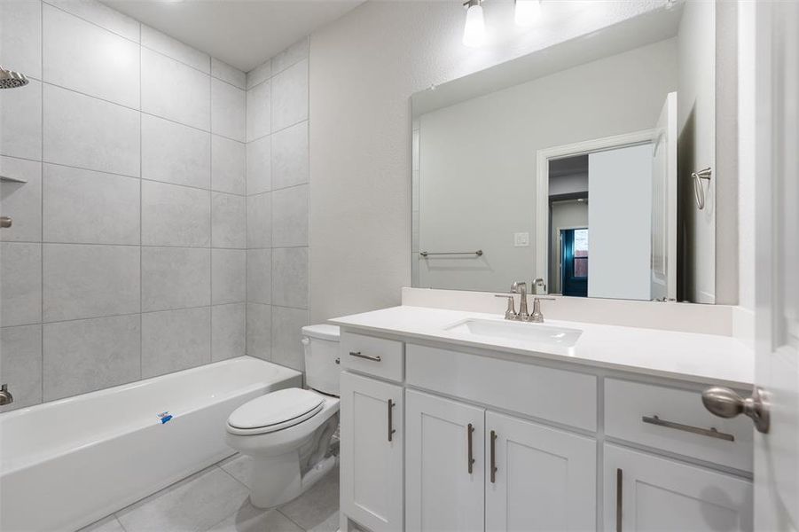 Full bath featuring shower / bathtub combination, vanity, and light tile patterned floors