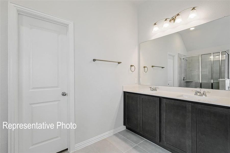 Bathroom with tile patterned flooring, an enclosed shower, double vanity, and vaulted ceiling