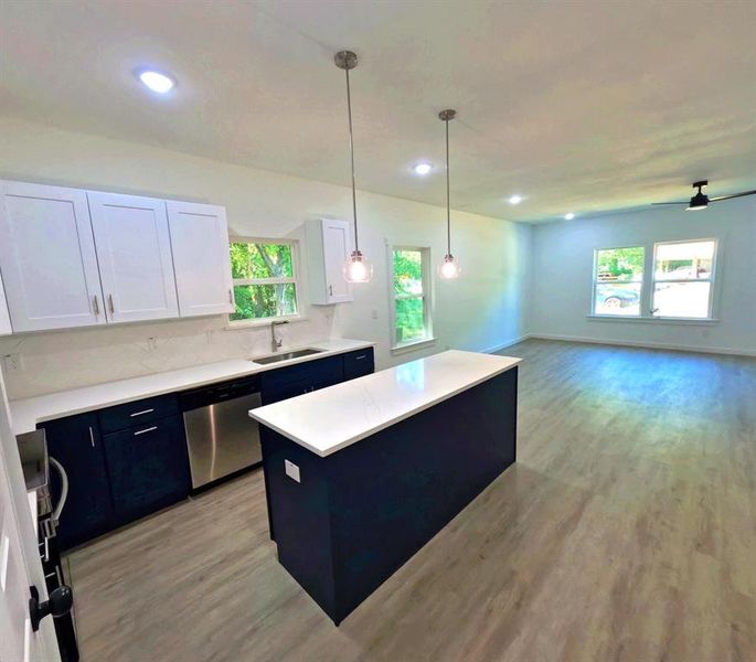 Kitchen with white cabinets, hanging light fixtures, a center island, blue cabinets, and dishwasher Kitchen with white cabinets, hanging light fixtures, a center island, blue cabinets, and dishwasher
