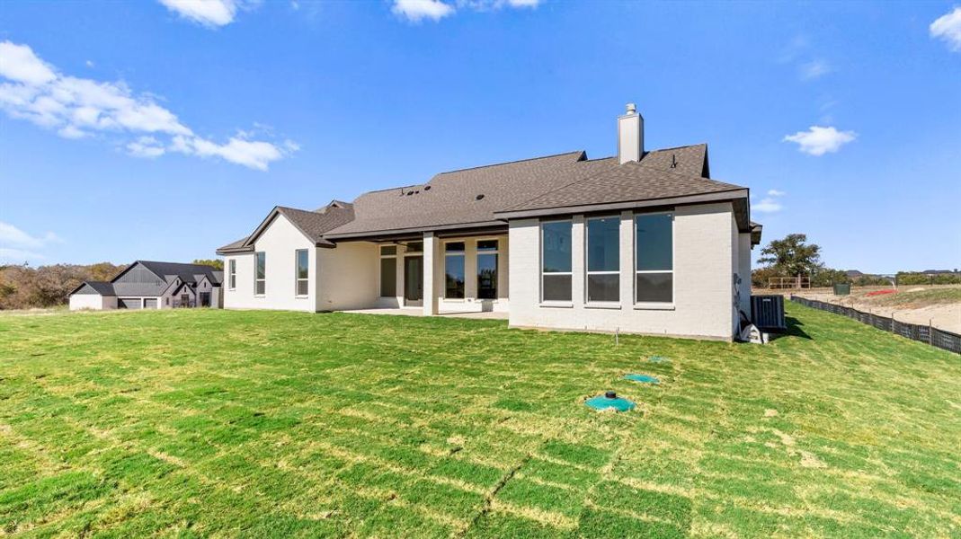 Rear view of property with ceiling fan, a patio area, a yard, and central AC