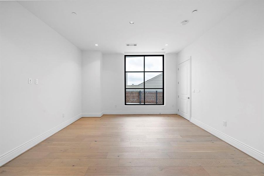 Primary bedroom: featuring light wood floors, high ceilings, & sizable window that fills the space with natural light. Complemented by large walls ideal for showcasing art.