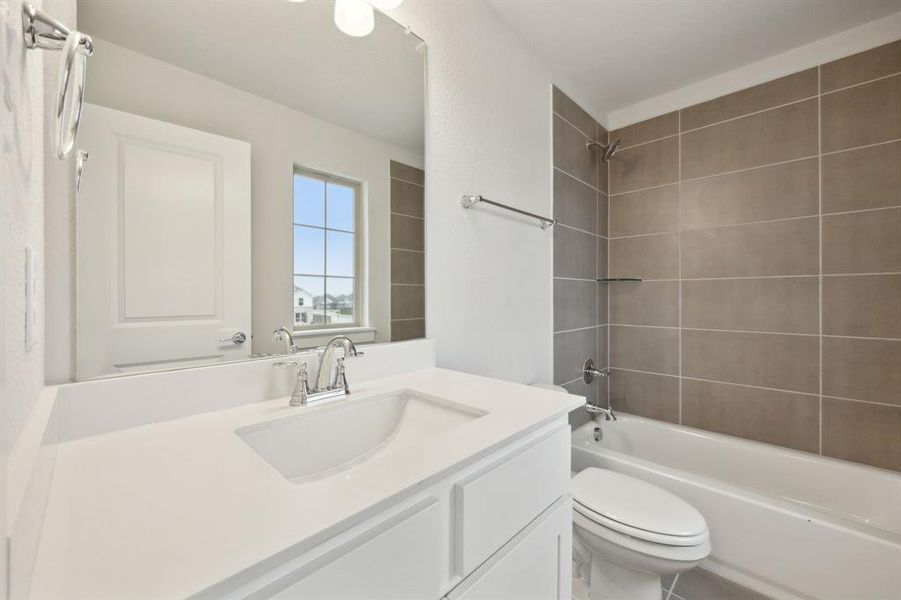 Full bathroom with tiled shower / bath, vanity, and toilet