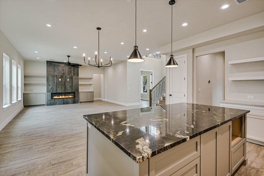 Kitchen featuring open floor plan, a tiled fireplace, a large island, and open shelves