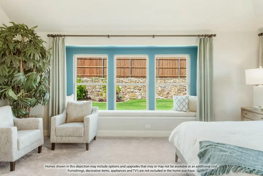 Bedroom with bay window seat, blue accent wall, two armchairs, and carpet flooring overlooking a backyard Bedroom with bay window seat, blue accent wall, two armchairs, and carpet flooring overlooking a backyard