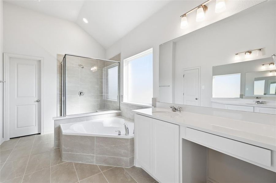 Full bathroom featuring a bath, vaulted ceiling, a stall shower, light tile patterned floors, and vanity