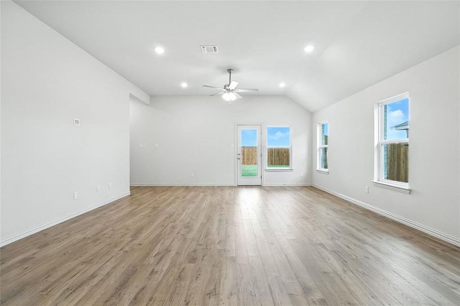 Unfurnished living room featuring light wood-style flooring, recessed lighting, lofted ceiling, and ceiling fan Unfurnished living room featuring light wood-style flooring, recessed lighting, lofted ceiling, and ceiling fan