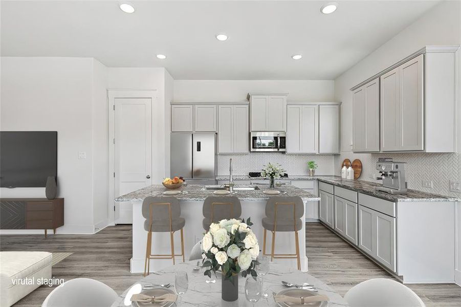 Kitchen featuring an island with sink, stainless steel appliances, and light wood-type flooring