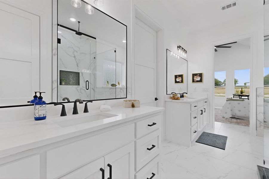 Bright bathroom featuring dual white vanities with integrated sinks and black hardware, large frameless mirrors, and black fixtures