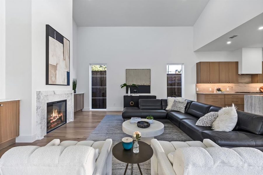 Living room with a high ceiling, dark hardwood / wood-style floors, and a premium fireplace