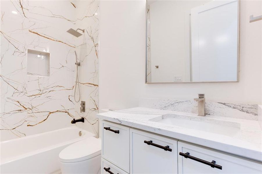 Full bathroom with vanity, tiled shower / bath combo, and toilet