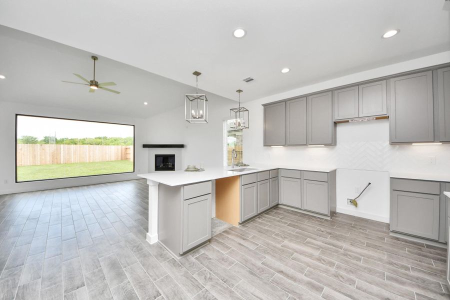 This kitchen is truly a chef's dream! This haven Boasts high ceilings, recessed & pendant lighting, stained wood cabinets, granite countertops, stainless steel appliances, a modern tile backsplash.  All of this overlooks your expansive family room, creating a perfect space for culinary delights and family gatherings. Sample photo of completed home with similar floor plan. Actual colors and selections may vary.