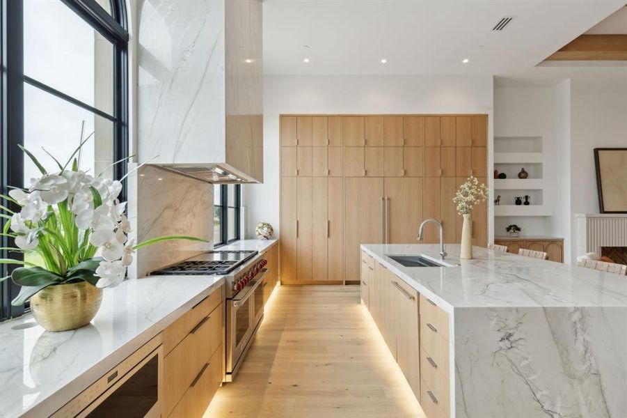 Kitchen featuring modern built-in cabinets, White oak floors, Wolf & SubZero appliances, light stone countertops, and recessed lighting Kitchen featuring modern built-in cabinets, White oak floors, Wolf & SubZero appliances, light stone countertops, and recessed lighting