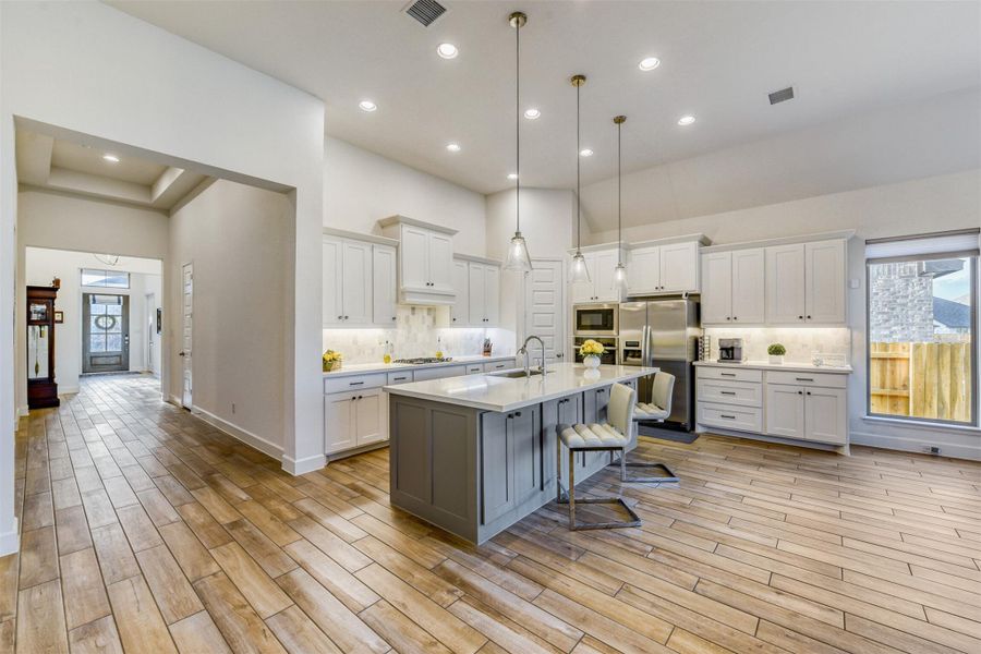 Two tone kitchen featuring healthy amount of natural light, decorative backsplash, a breakfast bar, two tone color scheme, and a high ceiling