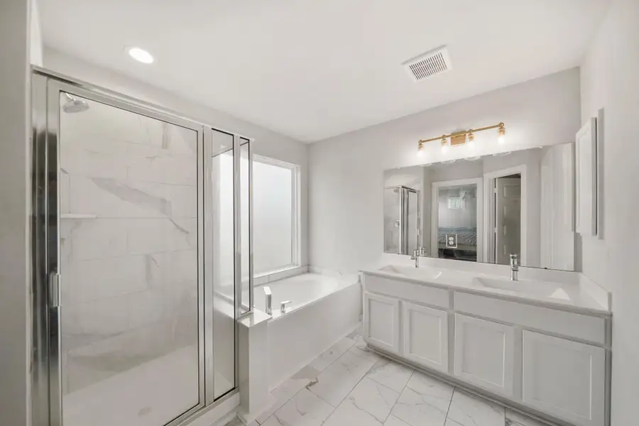 Relax after a long day in this wonderful primary bathroom with a garden tub, glass enclosed shower, double sinks, and modern fixtures.