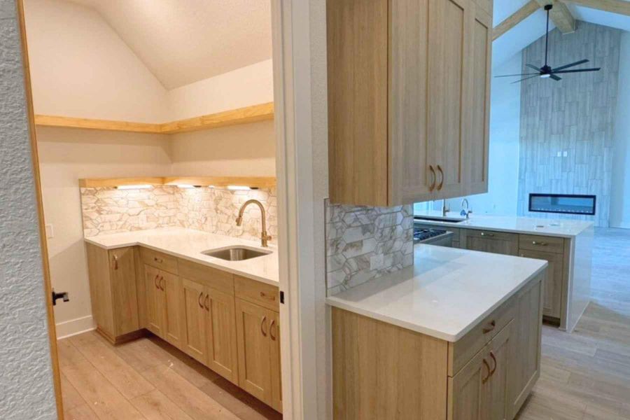 Kitchen with light brown cabinetry, light stone counters, light wood-type flooring, and ceiling fan