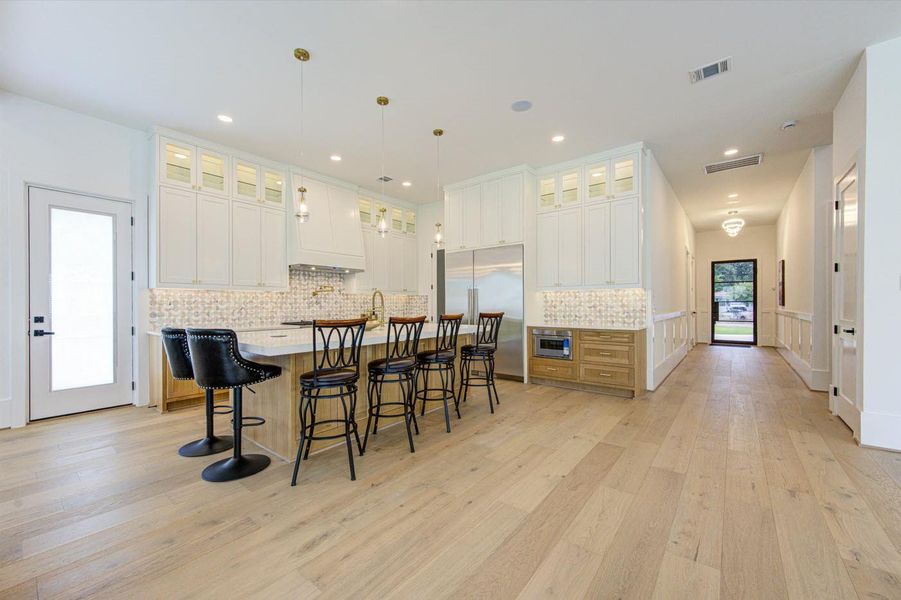 Grand kitchen island (9 ft by 5 ft) with cabinetry on both sides and seating for six, designed with comfortable legroom.