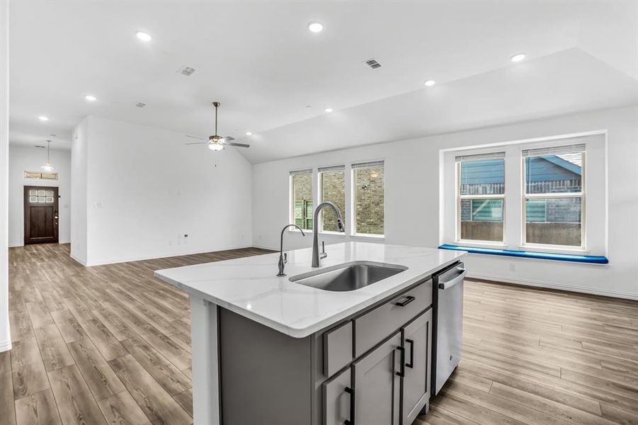 Kitchen island featuring a stainless steel sink with a gooseneck faucet, light grey cabinetry, and a white countertop