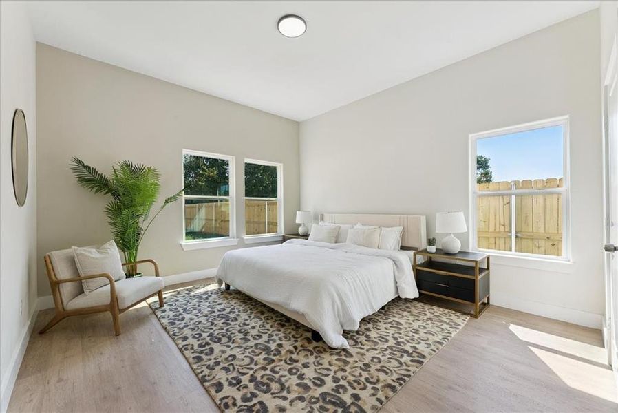 Bedroom with multiple windows and light wood-style flooring