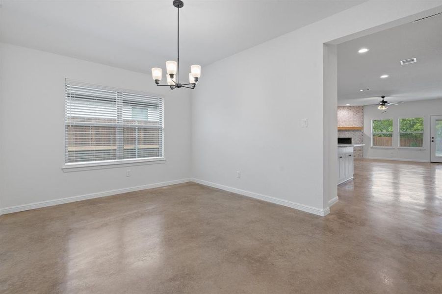 Spare room featuring ceiling fan with notable chandelier and a large fireplace