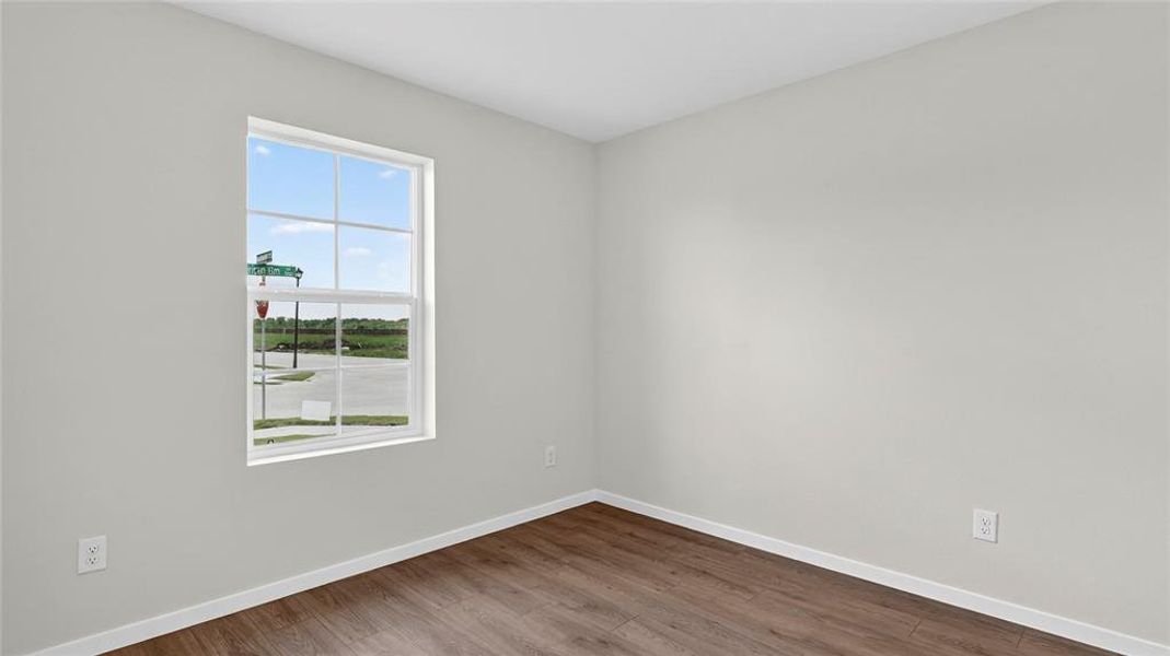 Bright interior room featuring a large grid window, wood-finish flooring, light-toned wall paint, white baseboards, and white trim