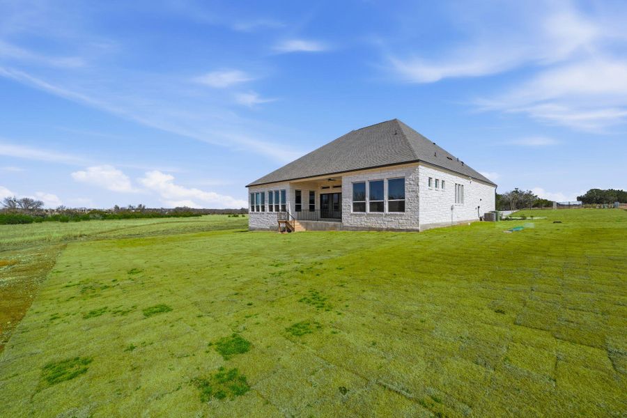 Back of property featuring stone siding, a lawn, ceiling fan, a patio area, and a view of rural / pastoral area