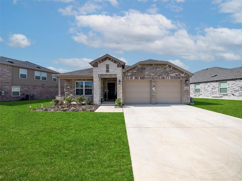 View of front of home featuring a front lawn, brick siding, and concrete driveway