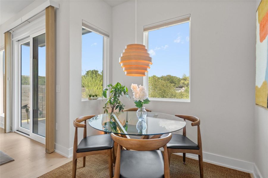 A breakfast nook with ample natural light, featuring a contemporary pendant light and a sliding glass door leading to the outdoors. A breakfast nook with ample natural light, featuring a contemporary pendant light and a sliding glass door leading to the outdoors.