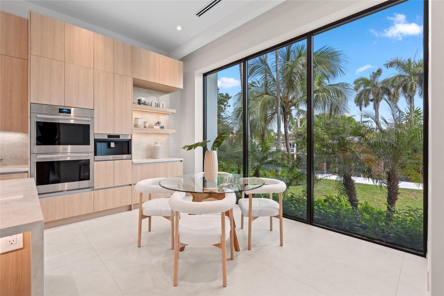 Bright breakfast nook with floor-to-ceiling windows, garden and water views, and seamless connection to the gourmet kitchen. Bright breakfast nook with floor-to-ceiling windows, garden and water views, and seamless connection to the gourmet kitchen.