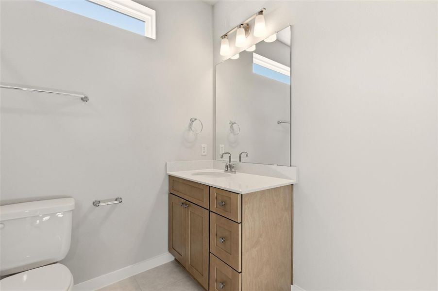 Half bath with healthy amount of natural light, vanity, and light tile patterned floors