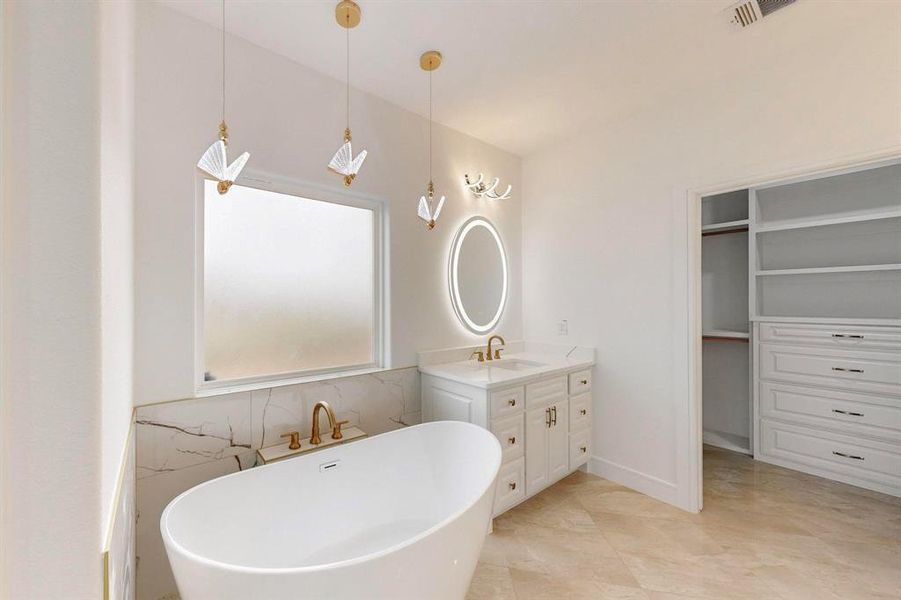Bathroom with vanity, a freestanding bath, and a walk in closet