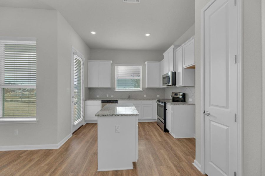 Kitchen featuring appliances with stainless steel finishes, white cabinetry, light wood-style floors, decorative backsplash, and recessed lighting