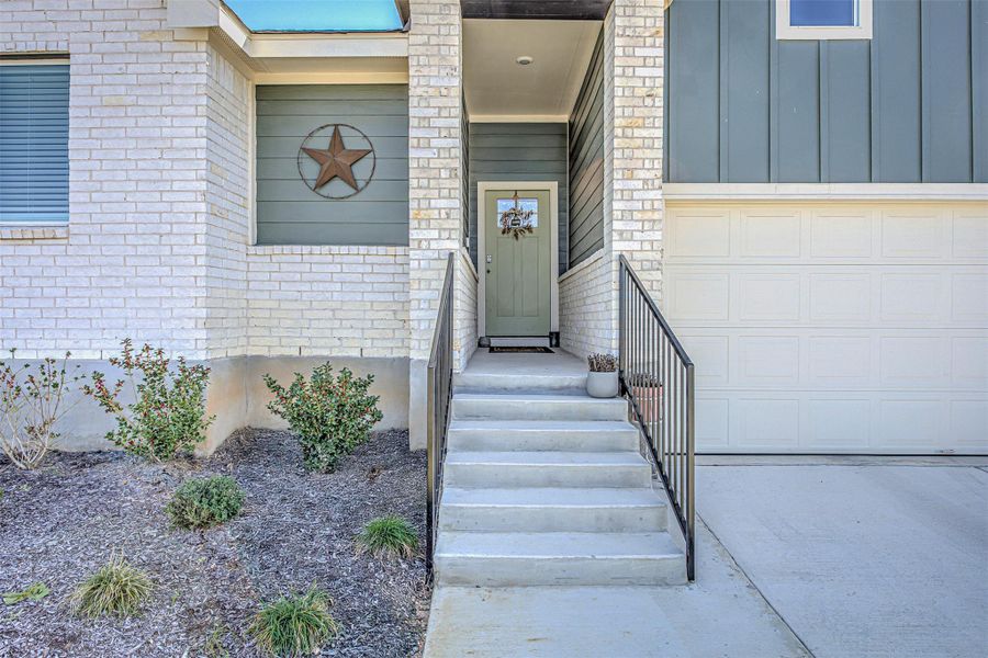 Entrance to property featuring brick siding, board and batten siding, a garage, and concrete driveway