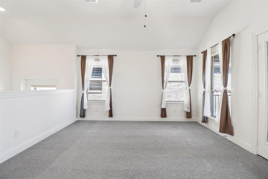 Spare room featuring ceiling fan, vaulted ceiling, and carpet Spare room featuring ceiling fan, vaulted ceiling, and carpet