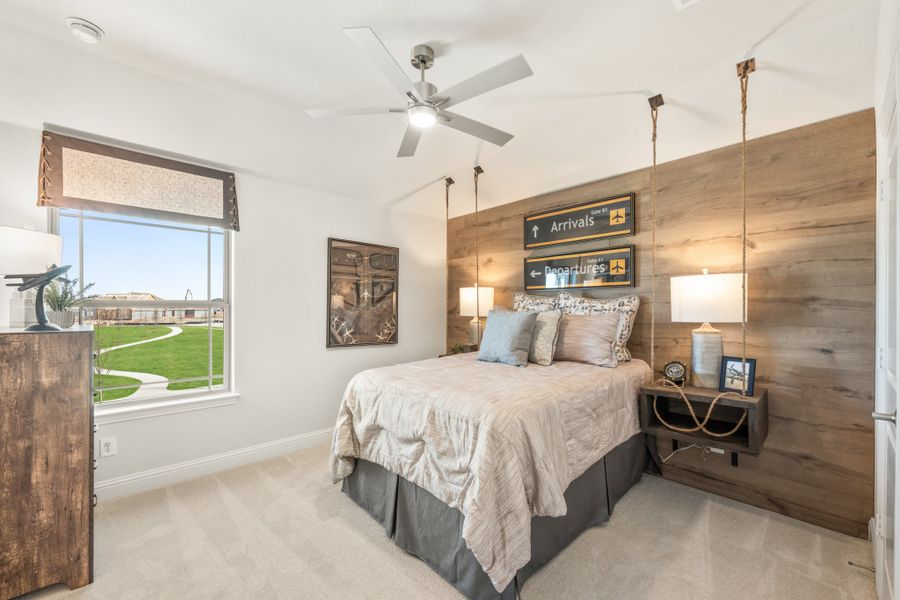 Bedroom with wood accent wall, ceiling fan, and hanging rope nightstands with airport-themed wall signs