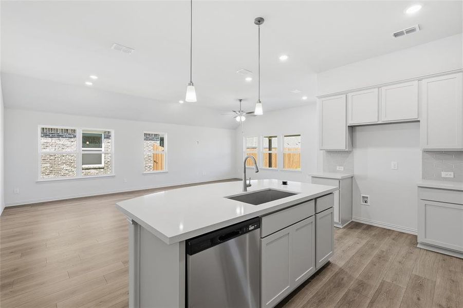 Kitchen with a kitchen island with sink, dishwasher, open floor plan, and tasteful backsplash