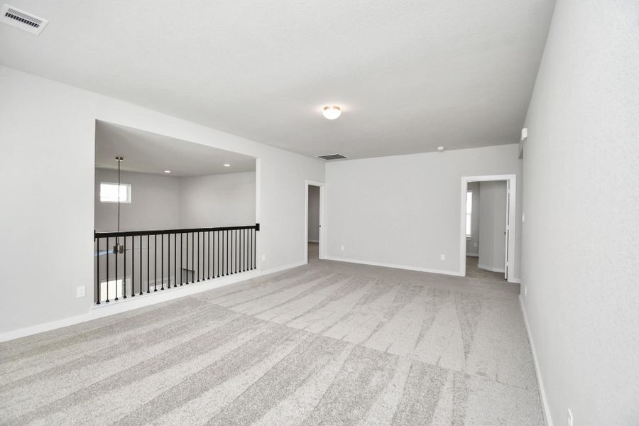 Ascend to relaxation in this fantastic game room! Ideal for both casual gatherings and adult gaming, it boasts plush carpet, lofty ceilings, custom paint, and ample windows for abundant natural light. Sample photo of completed home with similar floor plan. Actual colors and selections may vary.
