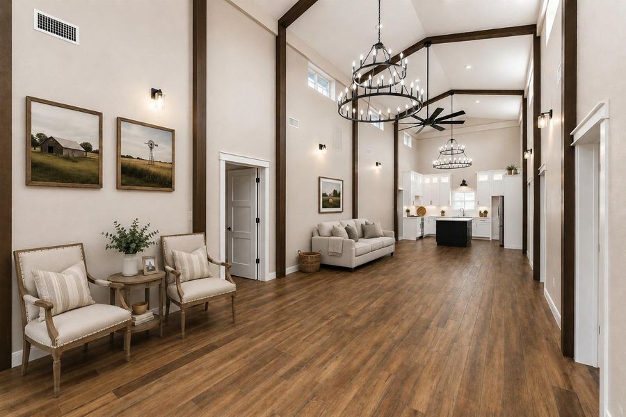 This spacious room features high ceilings with elegant chandeliers and exposed beams, complemented by warm tile wood-style flooring. It leads into a modern kitchen with white cabinetry and an island, offering an open, airy feel perfect for both entertaining and everyday living. AI decorated photo. This spacious room features high ceilings with elegant chandeliers and exposed beams, complemented by warm tile wood-style flooring. It leads into a modern kitchen with white cabinetry and an island, offering an open, airy feel perfect for both entertaining and everyday living. AI decorated photo.