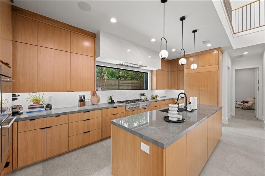 Kitchen featuring modern cabinets, a kitchen island with sink, decorative light fixtures, dark stone counters, and recessed lighting