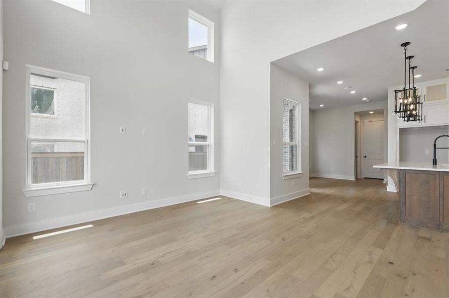 Unfurnished living room with light wood-style floors, recessed lighting, and a towering ceiling