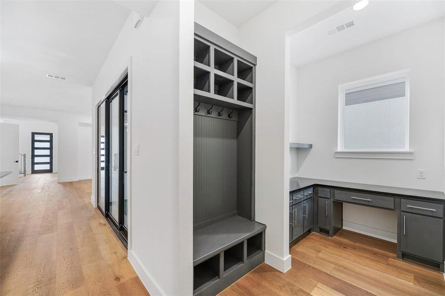 Mudroom featuring light wood-style floors, built in study area, visible vents, and baseboards