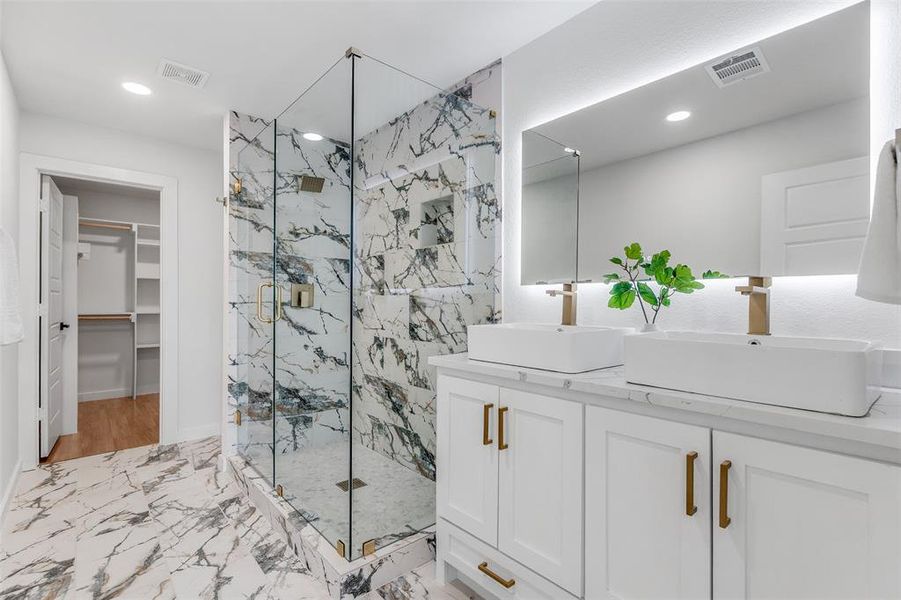 Full bath featuring a spacious closet, a marble finish shower, double vanity, light marble finish flooring, and recessed lighting Full bath featuring a spacious closet, a marble finish shower, double vanity, light marble finish flooring, and recessed lighting