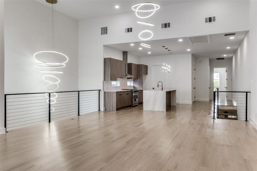 Unfurnished living room featuring a high ceiling, light wood finished floors, and recessed lighting