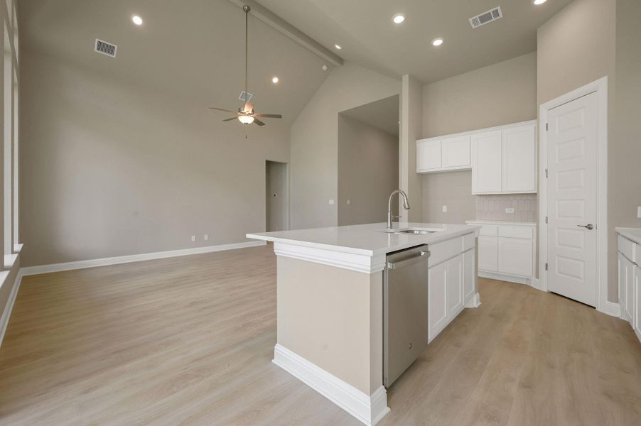 Kitchen featuring an island with sink, light wood-style floors, backsplash, stainless steel dishwasher, and recessed lighting