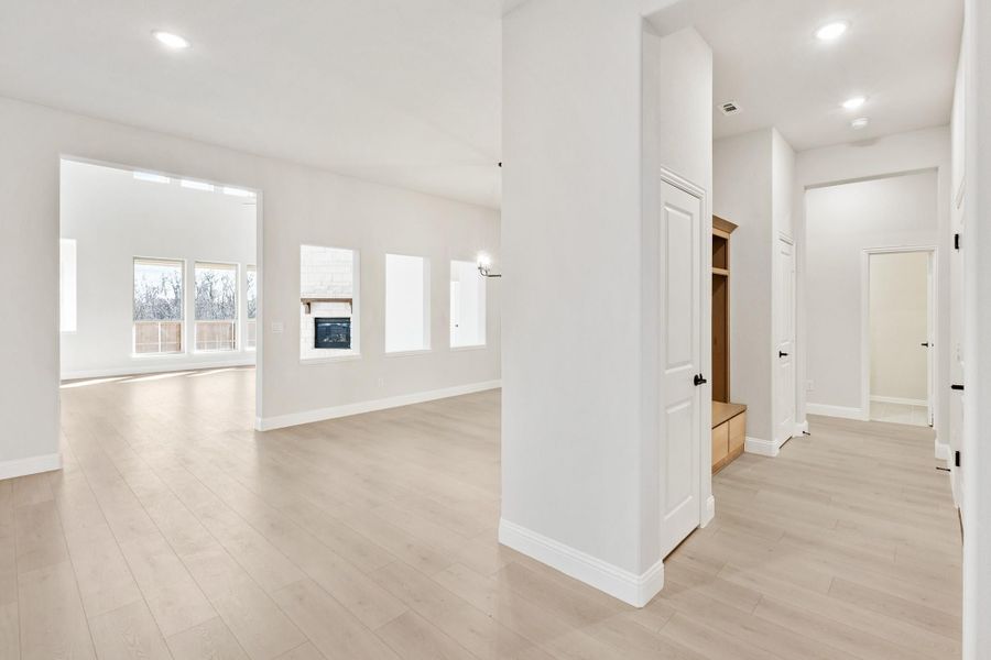 Open living area with light hardwood floors, fireplace, and mudroom with built-in storage cubbies