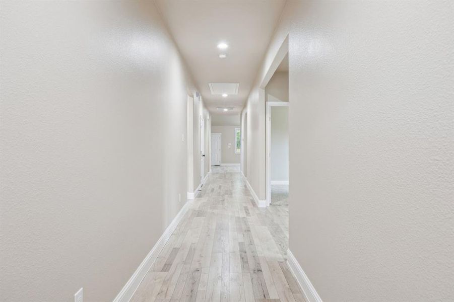 Entry Hallway looking to the back on the home featuring light wood finished floors, a textured wall, and recessed lighting. On the right side are two bedrooms. Entry Hallway looking to the back on the home featuring light wood finished floors, a textured wall, and recessed lighting. On the right side are two bedrooms.