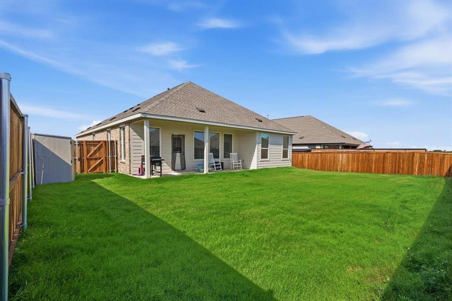 Expansive backyard featuring a lush lawn, privacy fencing, and a covered patio area Expansive backyard featuring a lush lawn, privacy fencing, and a covered patio area
