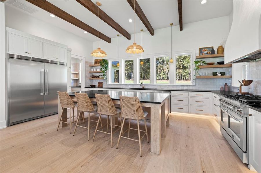 Kitchen with open shelves, hanging light fixtures, custom exhaust hood, decorative backsplash, and high quality appliances