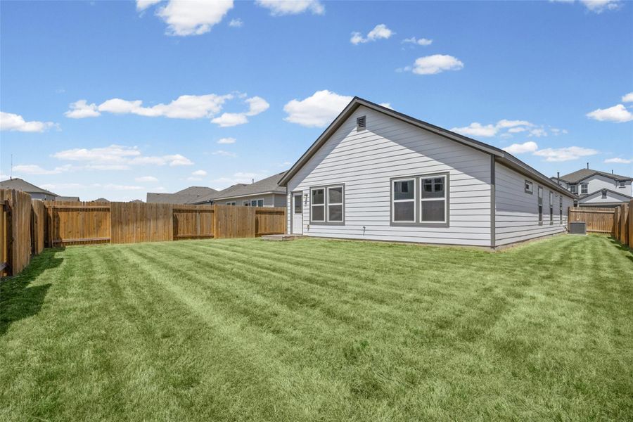 An expansive green lawn stretches across the fully fenced backyard of this modern home. An expansive green lawn stretches across the fully fenced backyard of this modern home.