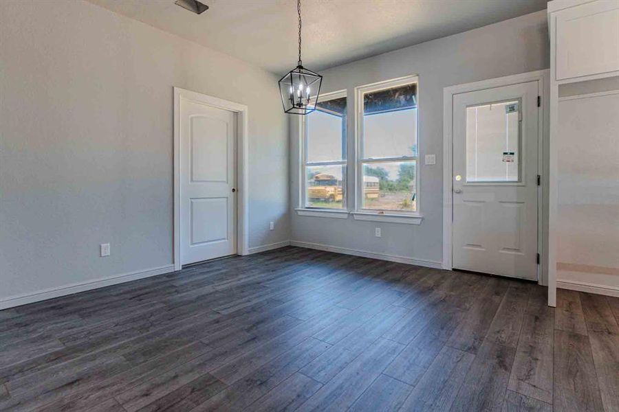 Unfurnished dining area with dark wood-style flooring and a chandelier Unfurnished dining area with dark wood-style flooring and a chandelier