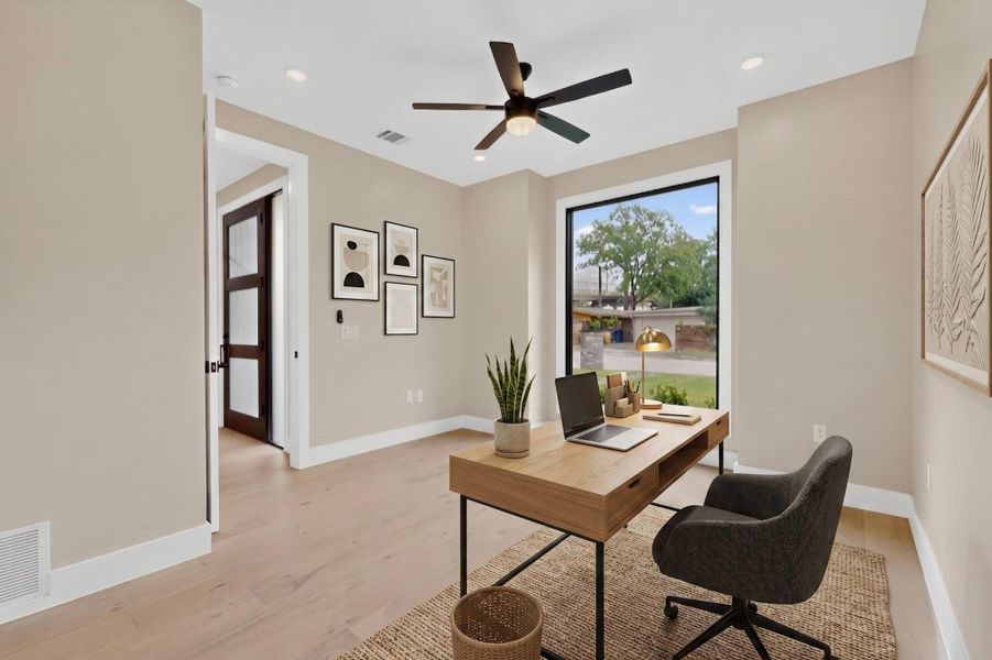 A dedicated home office provides a quiet space for productivity, featuring light wood flooring and a wide window view.